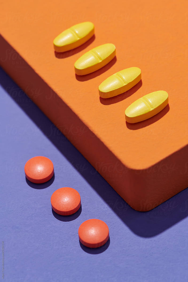 Yellow Capsules and Pills on  orange podium on  textured background