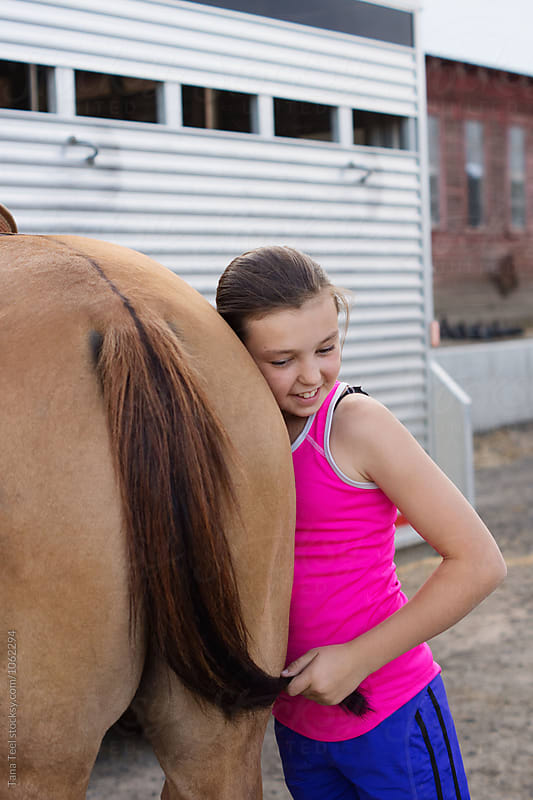 smiling girl holds horse\'s tail