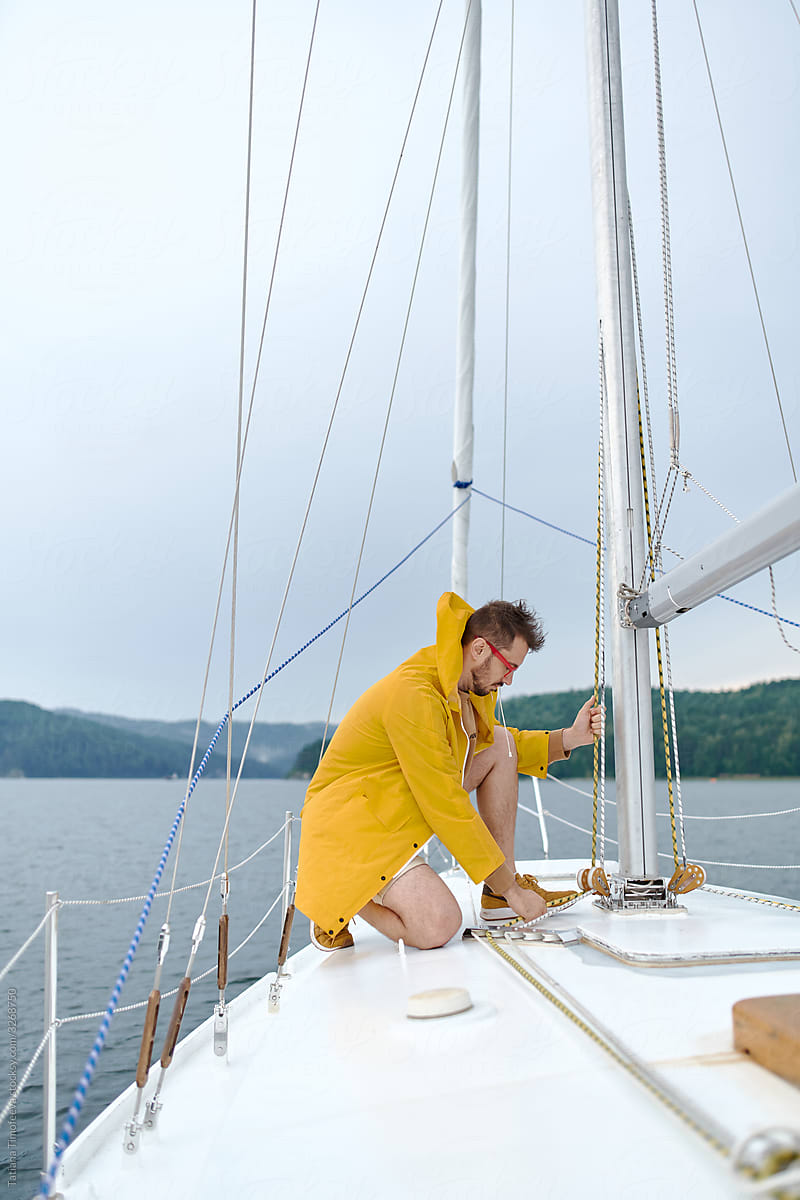 A male captain in a yellow raincoat on a white yacht