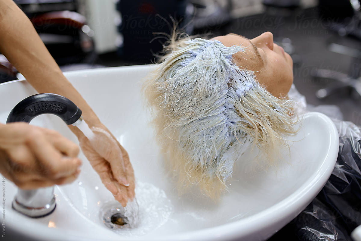 the hair master washes the client\'s head from hair dye