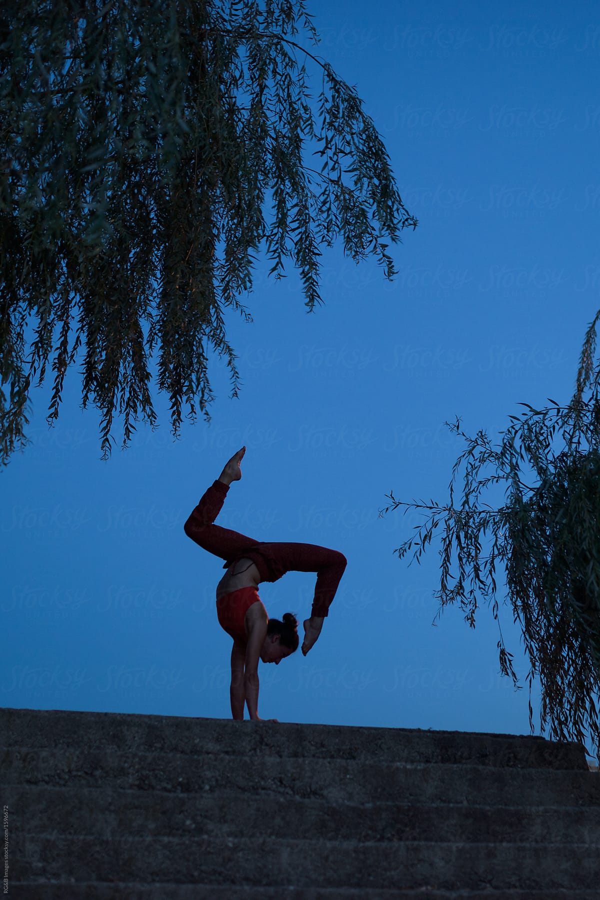 Female's silhouette practicing yoga outdoor in the twilight