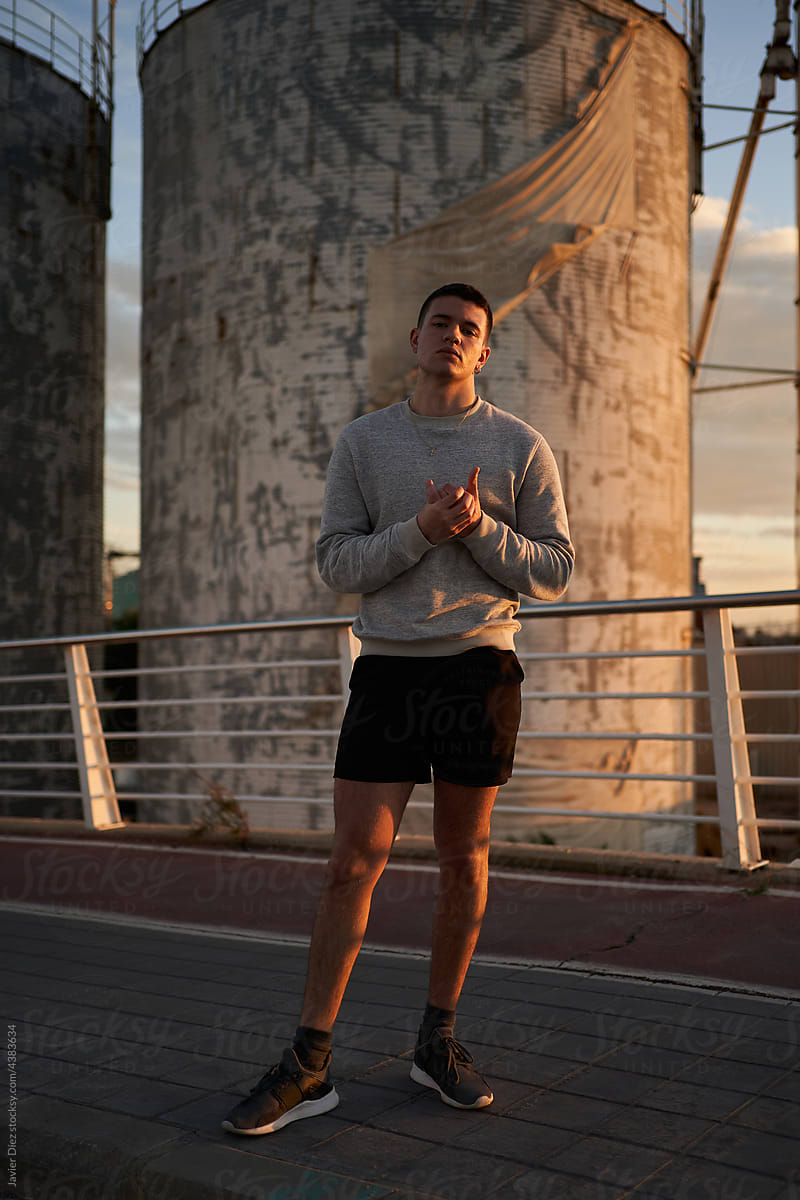 Self assured sportsman standing on bridge in sunset
