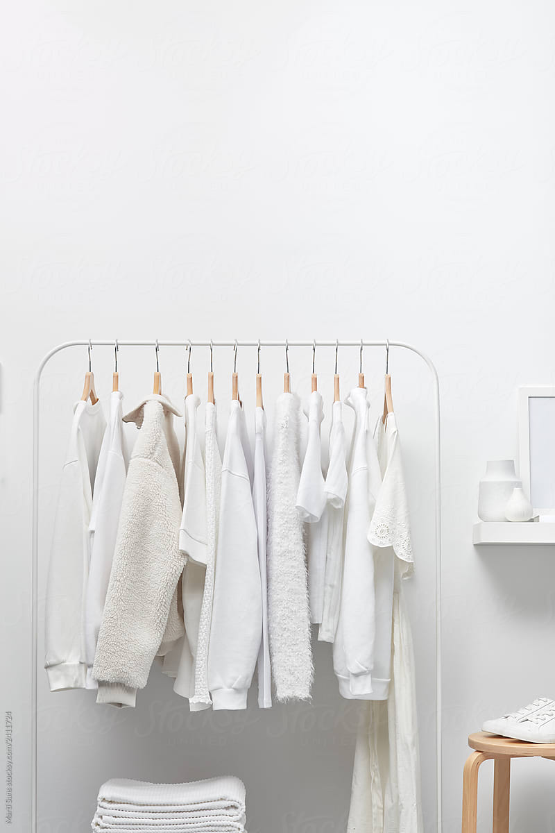 White cloakroom interior with clothing on hangers
