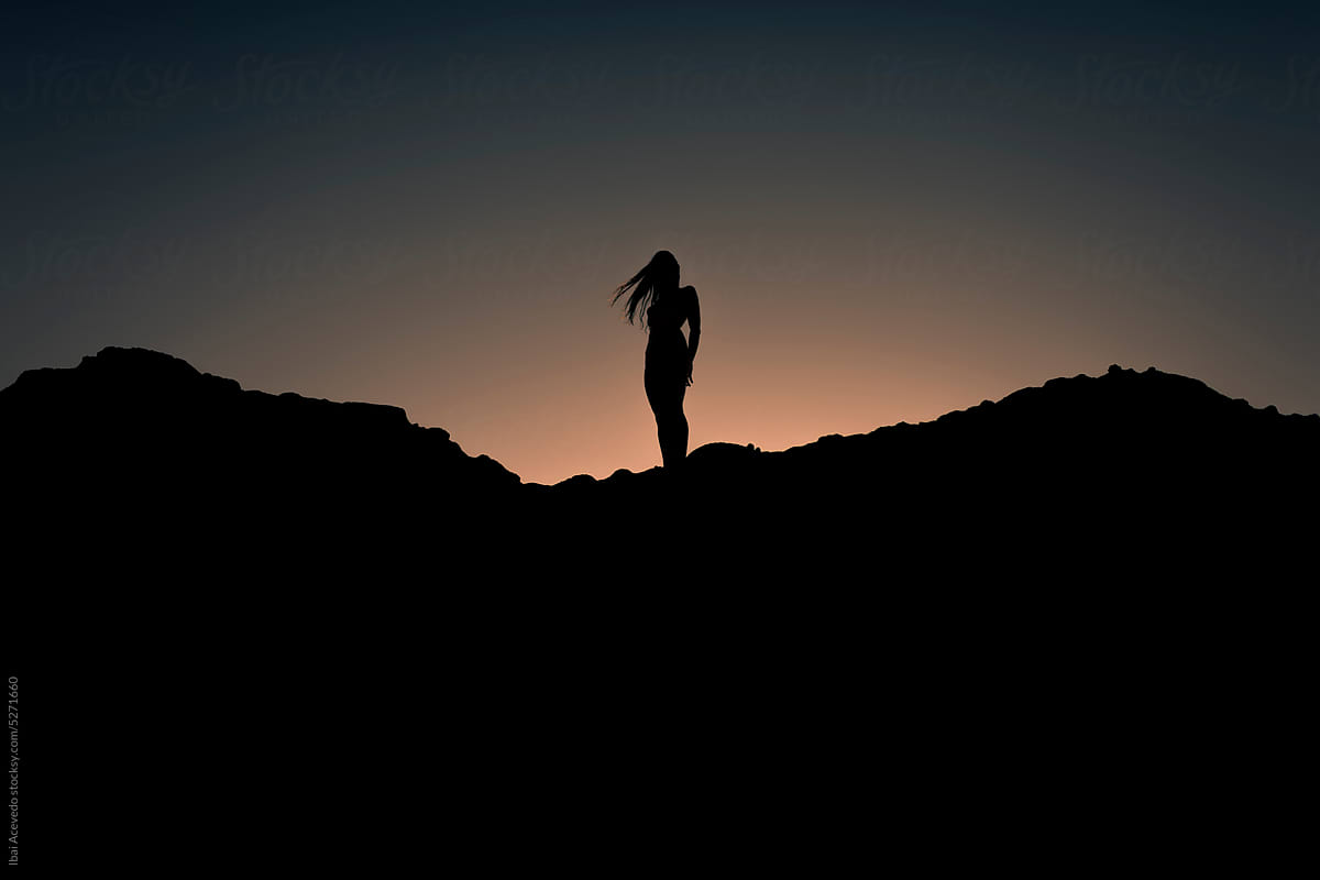 Woman body silhouette standing on dark hill