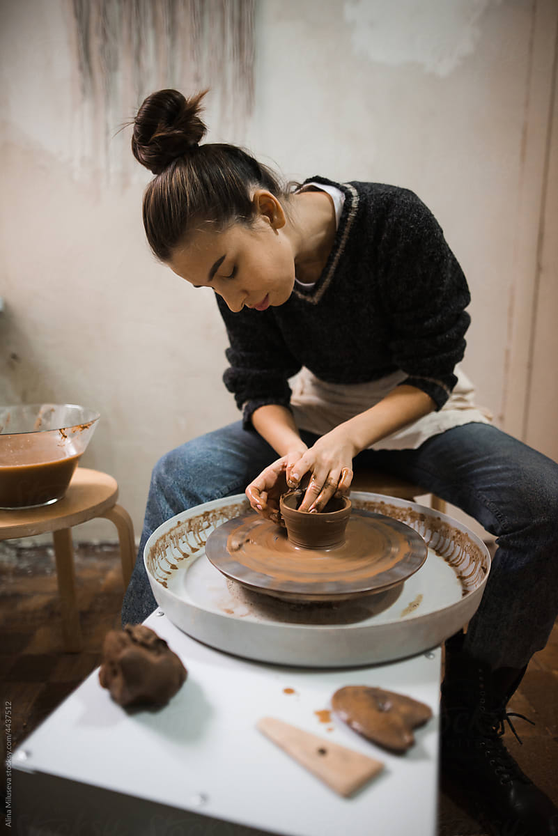 Young craftswoman using pottery wheel in her workshop