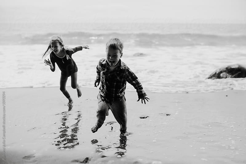 Young kids running away from ocean waves in winter or spring