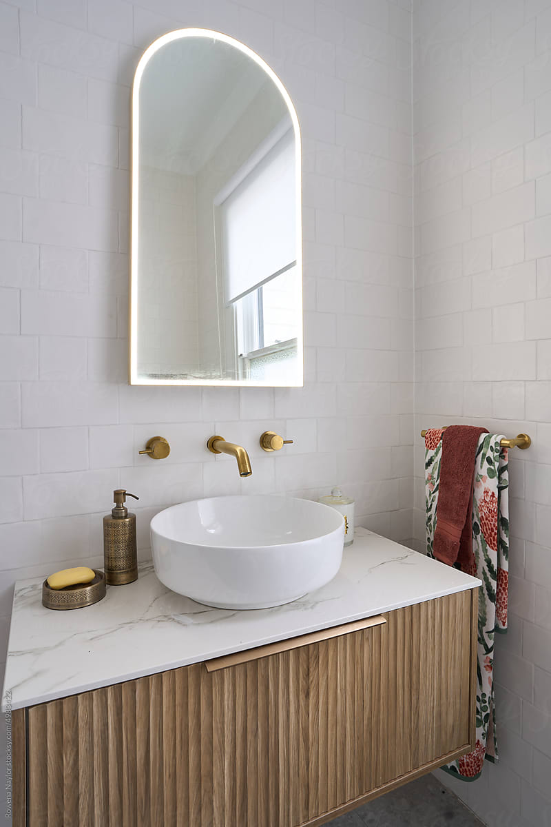 Stylish bathroom with brass tap ware and illuminated mirror