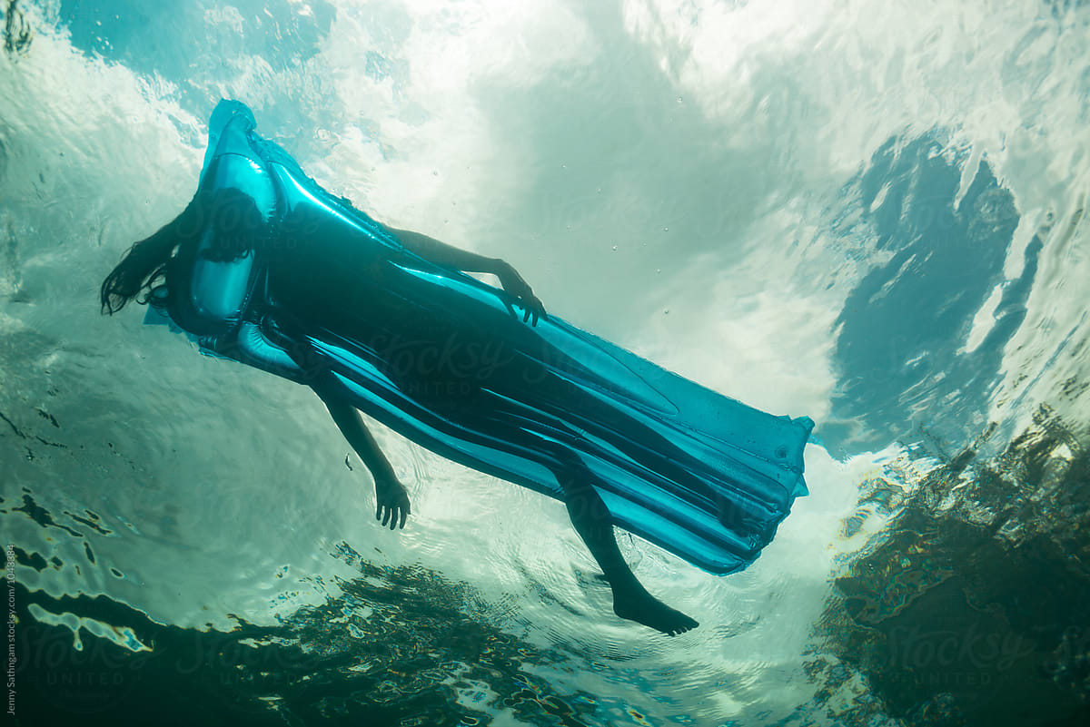 Underwater photo of a beautiful young woman swimming with a float