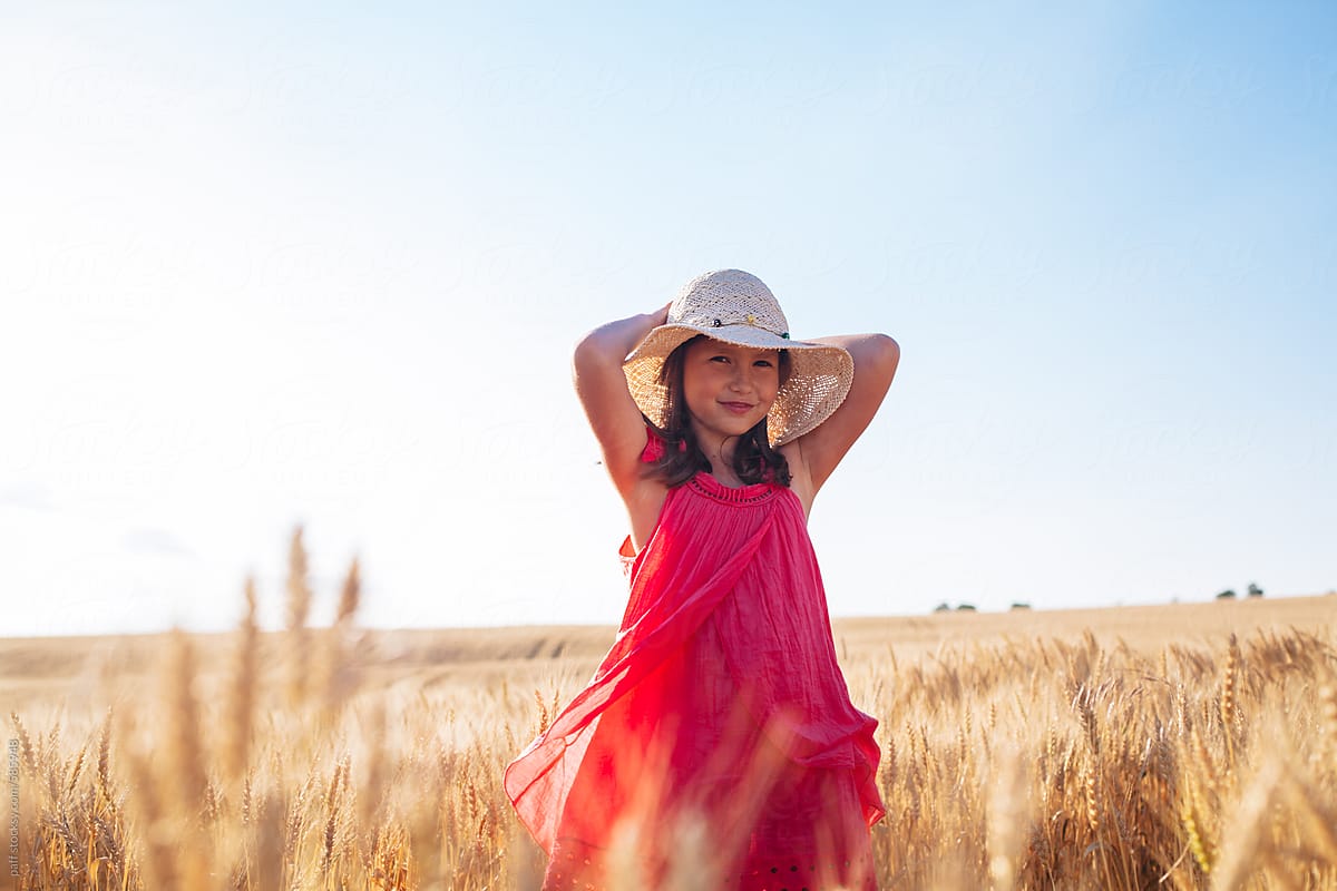 Portrait of a beautiful little girl in pink dress posing on a wheat field