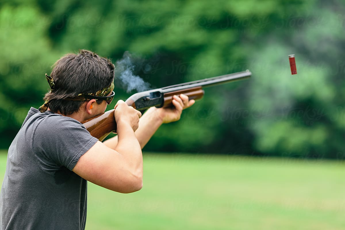 Man firing his shotgun while skeet shooting