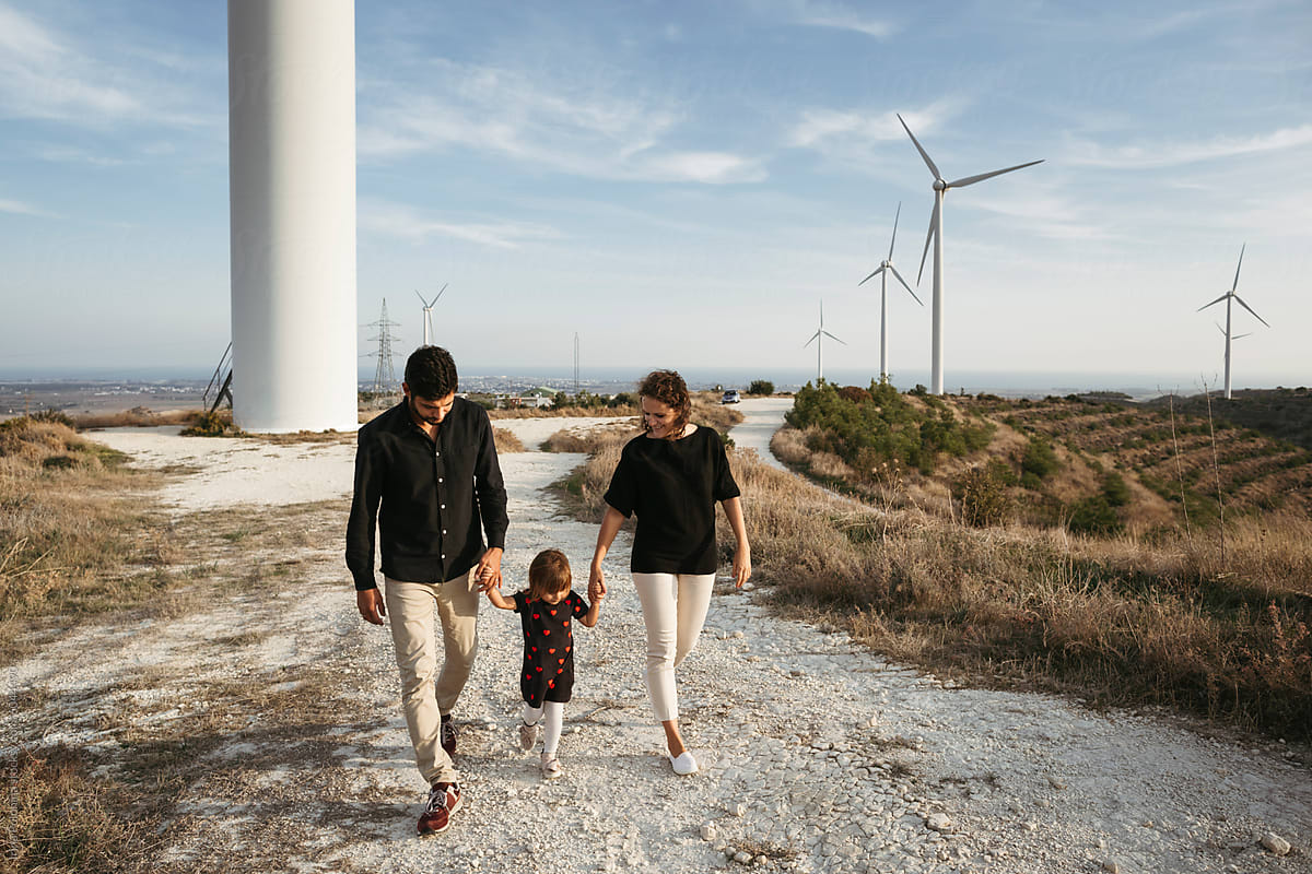 Family Walk by Wind Turbines at Dusk