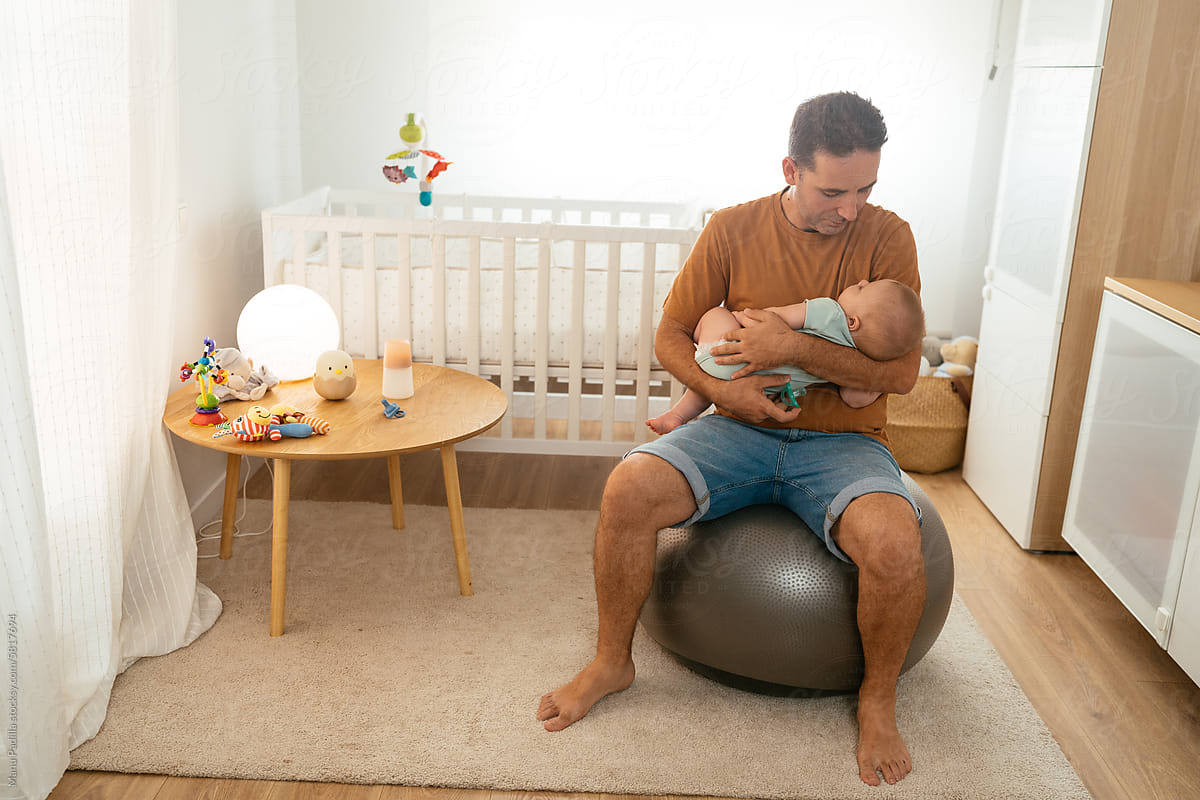 Dad lulling baby on fit ball