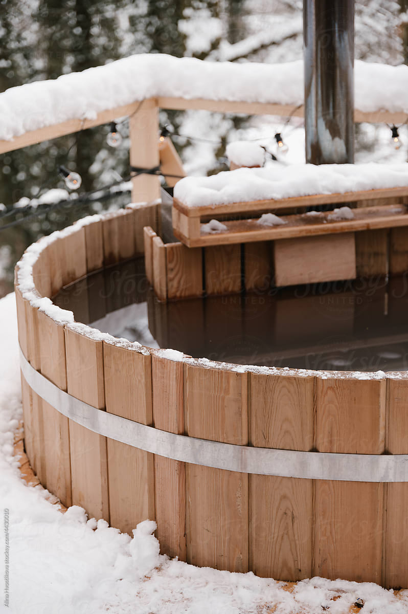 Wooden hot tub with water in winter forest