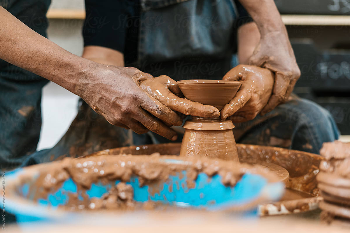 Anonymous hands of two potters creating on the potter\'s wheel