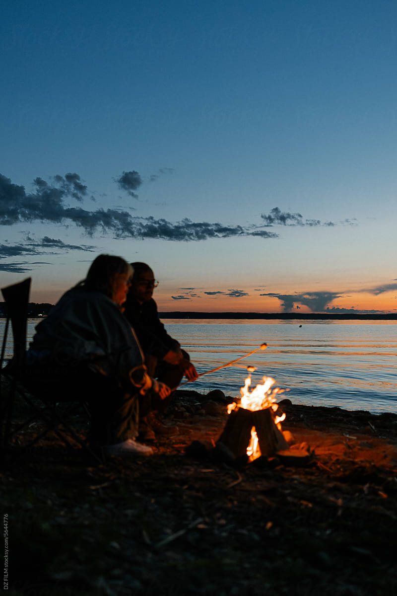 A man and a woman roast marshmallows on a bonfire