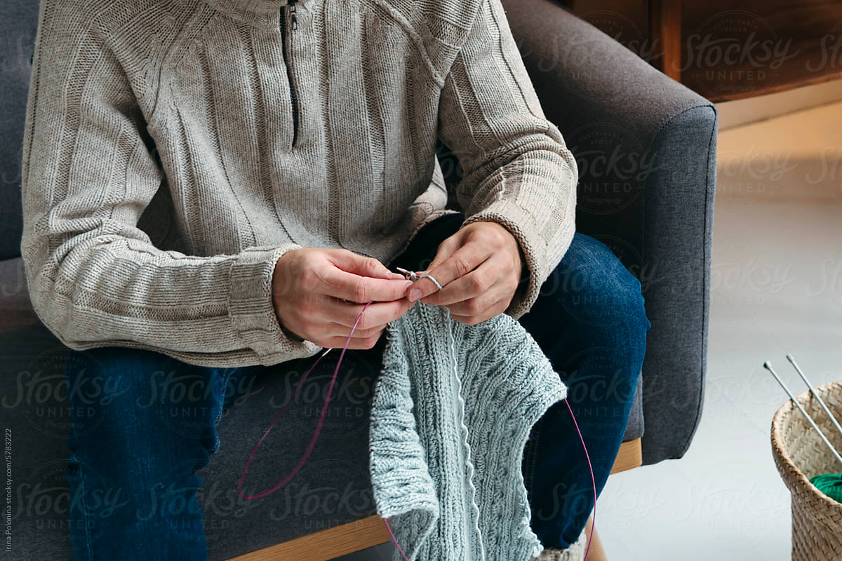 Faceless male knitting.