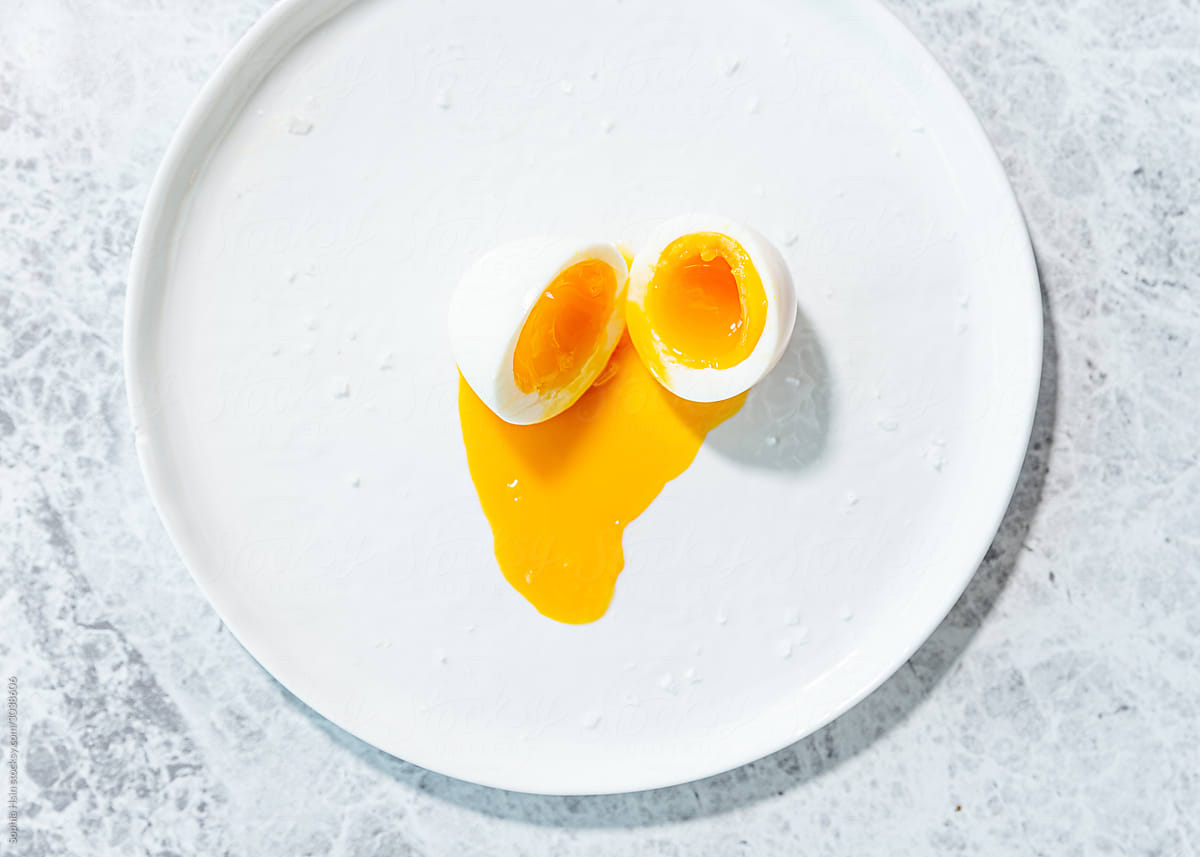 Runny soft boiled egg on white plate