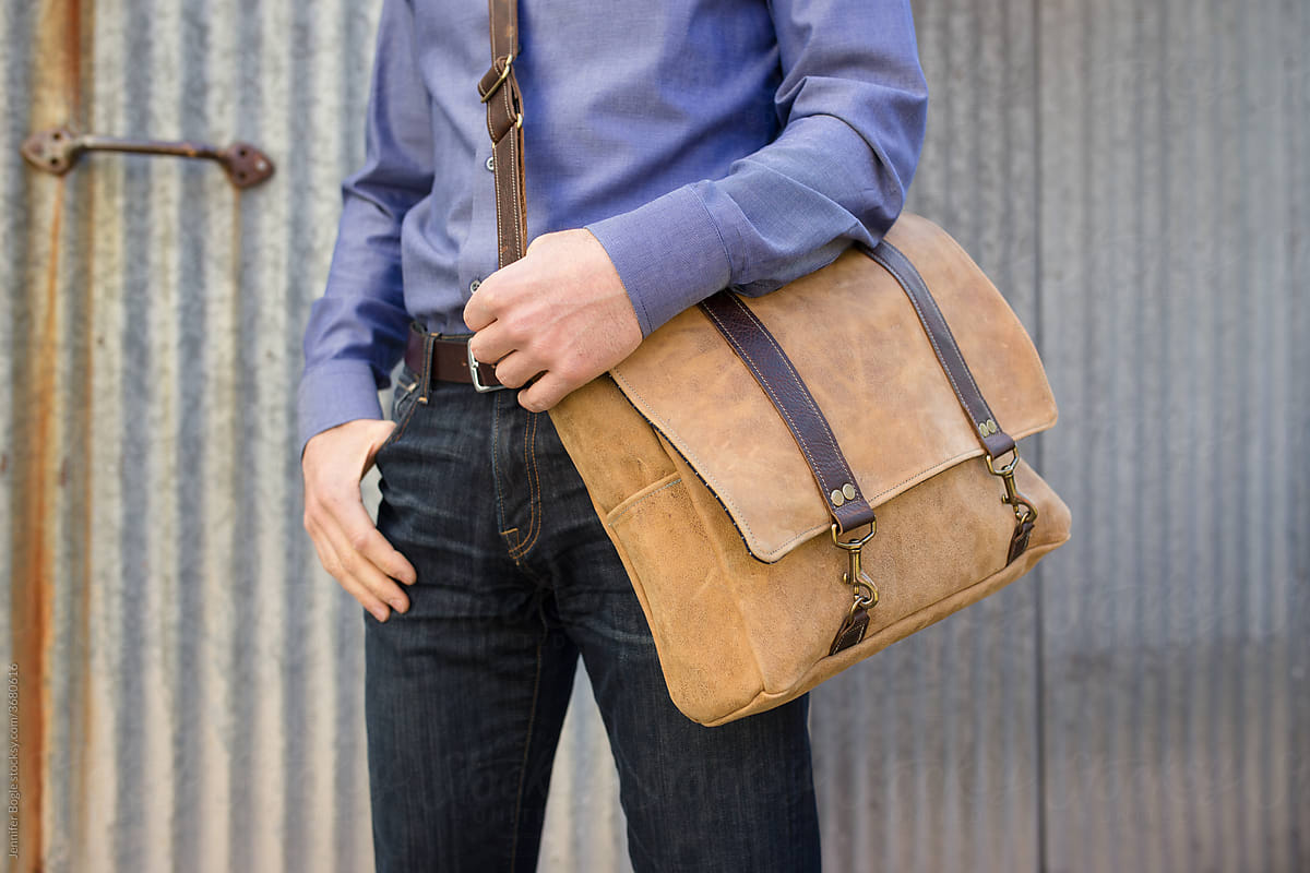 Man poses with leather messenger bag