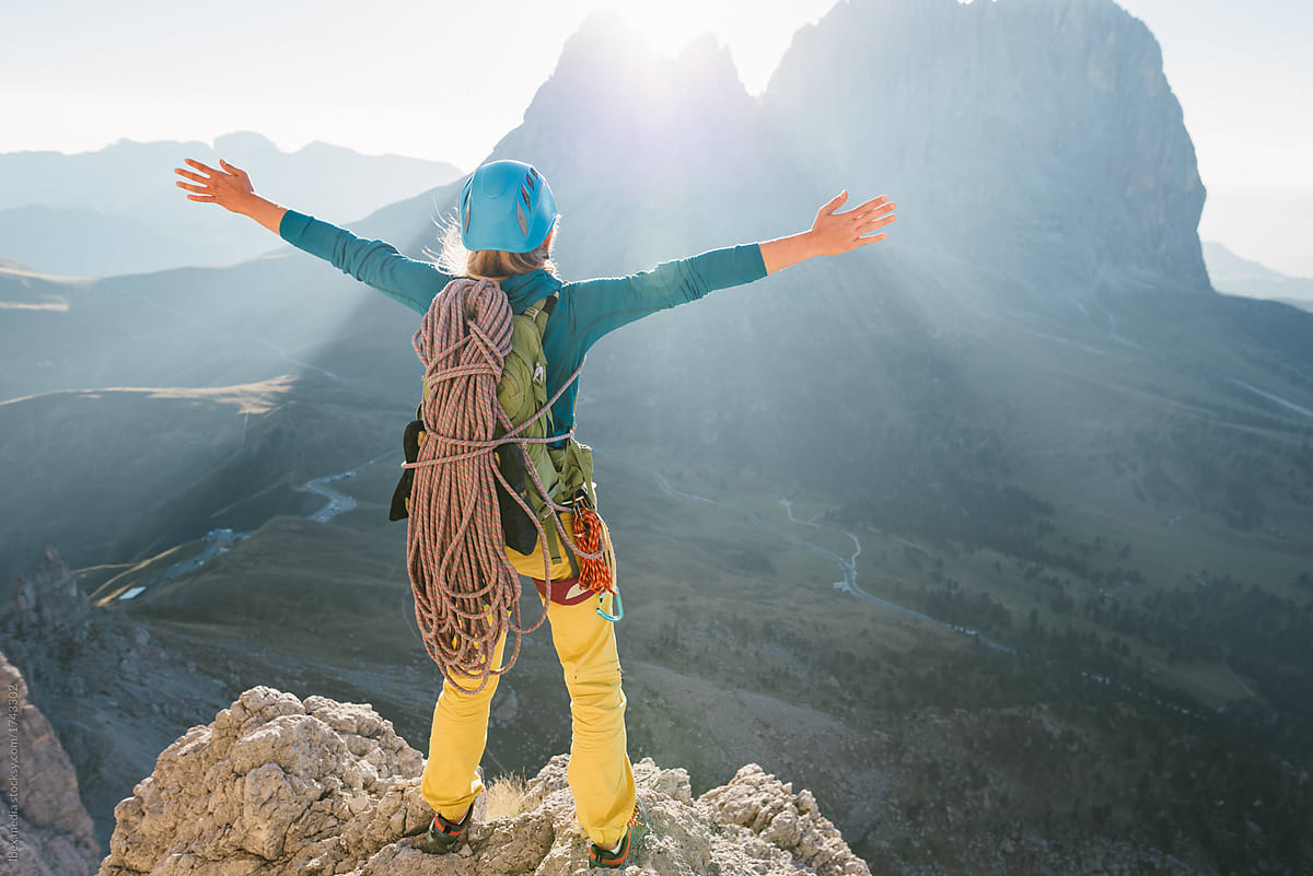 Female alpinist with arms outstretched on top of the mountain