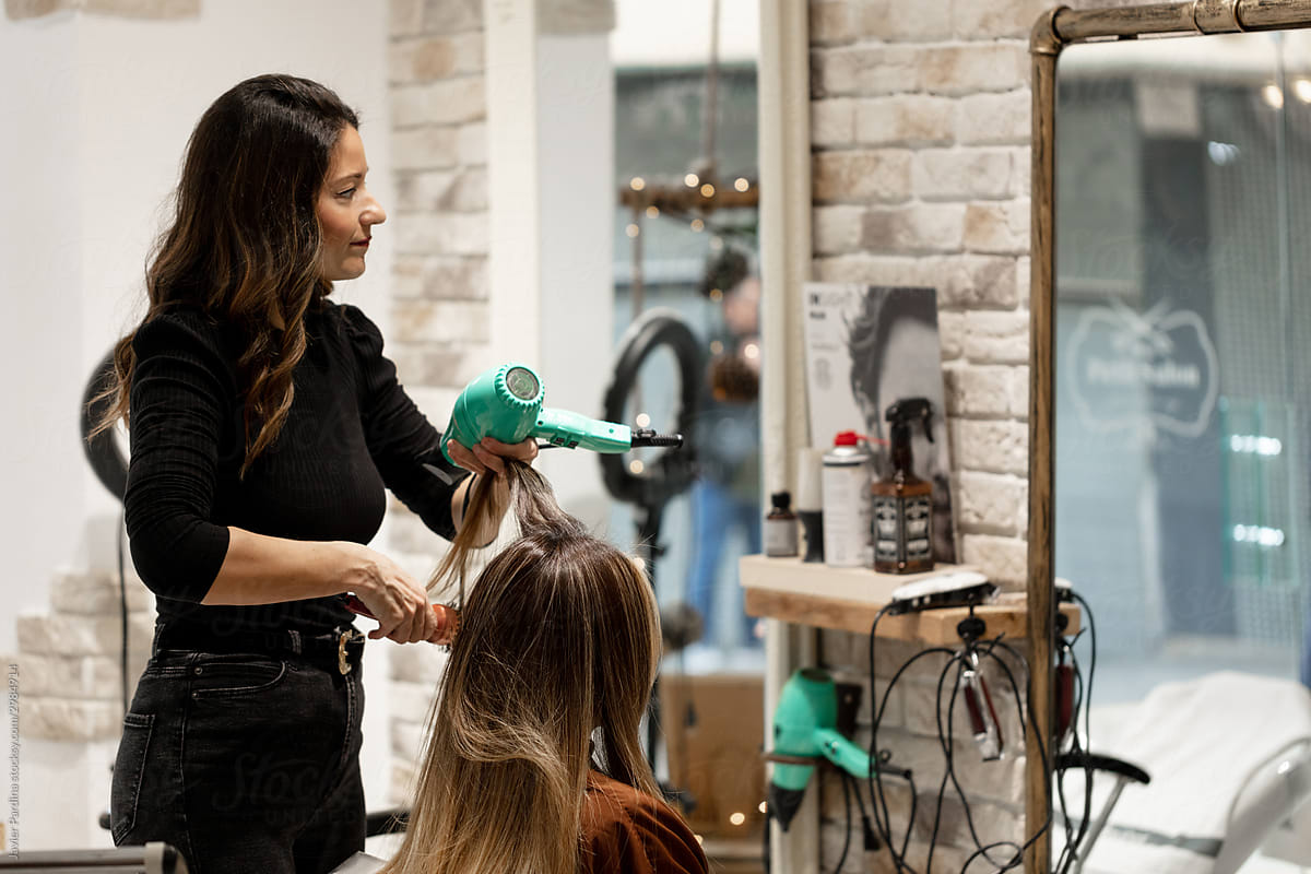 Hairdresser drying hair of woman