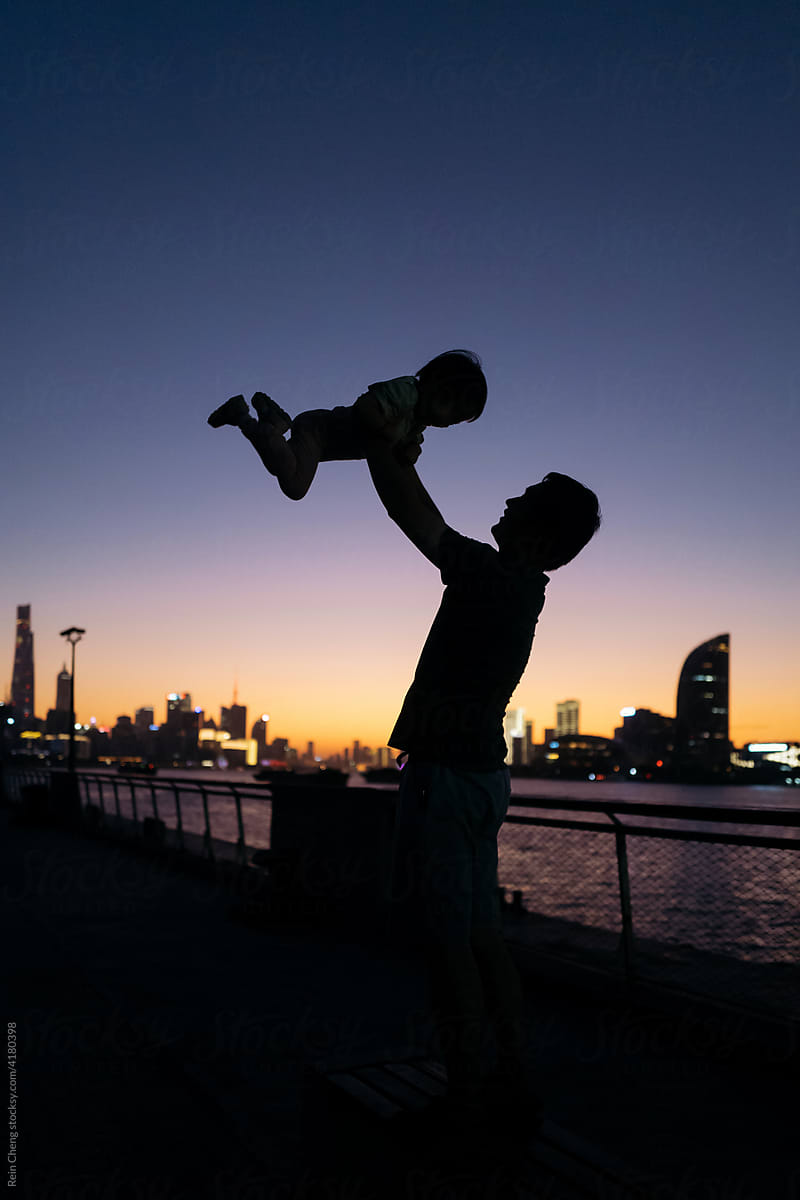 Silhouette of dad holding up baby
