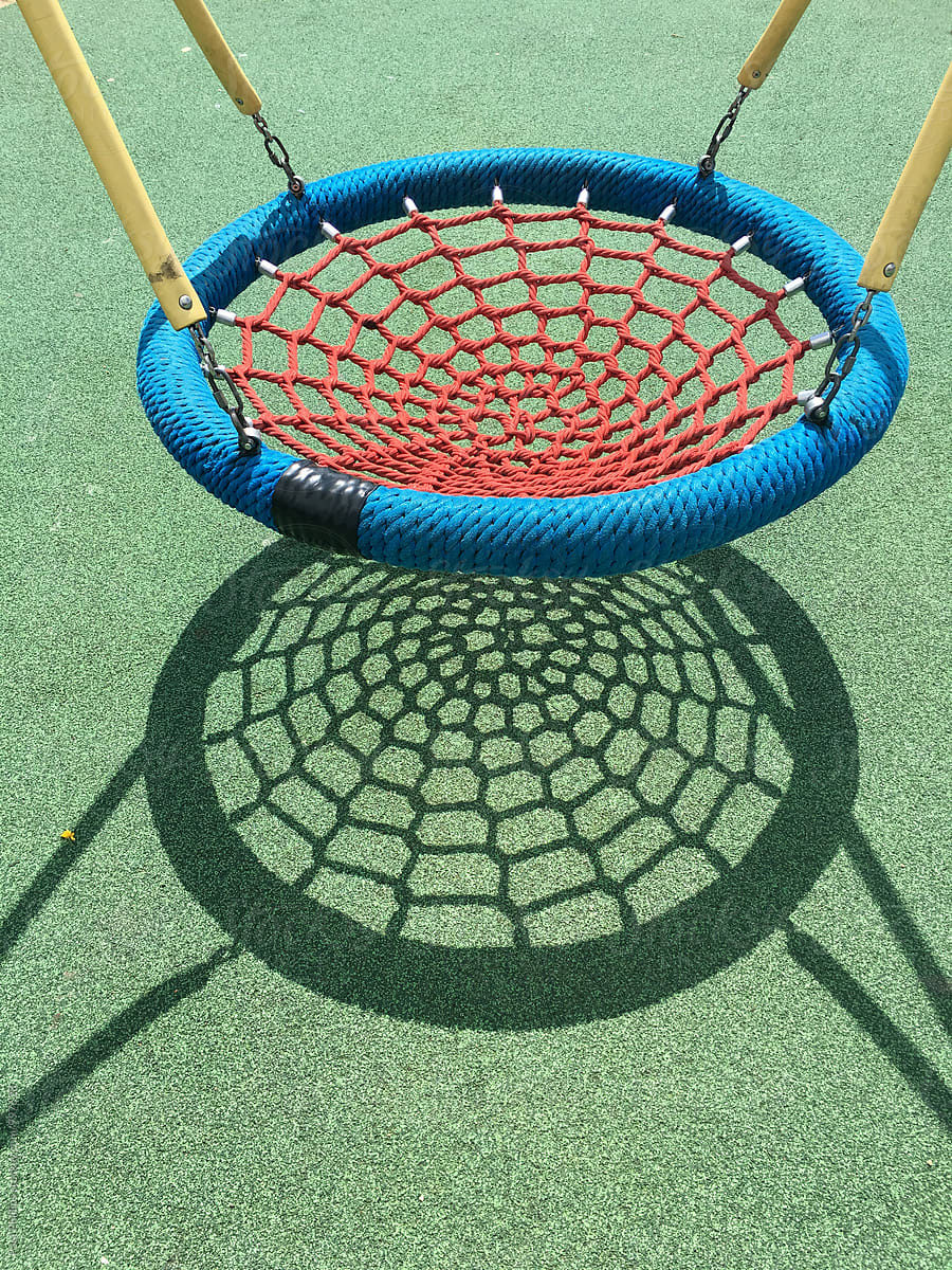 Children playground. Swing with strong shadow on safety  flooring.