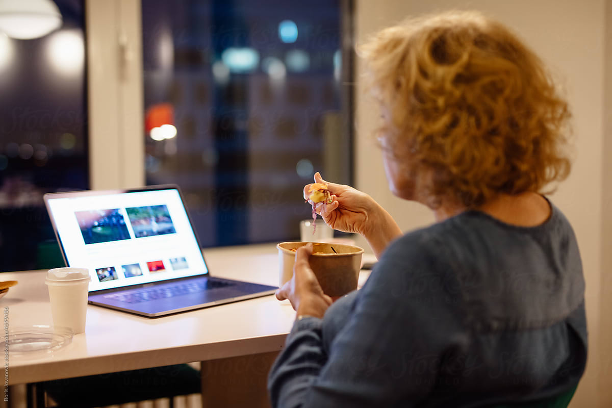 A woman is having dessert while looking at the computer