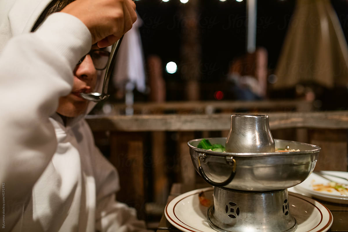Teen boy eating asian soup at night