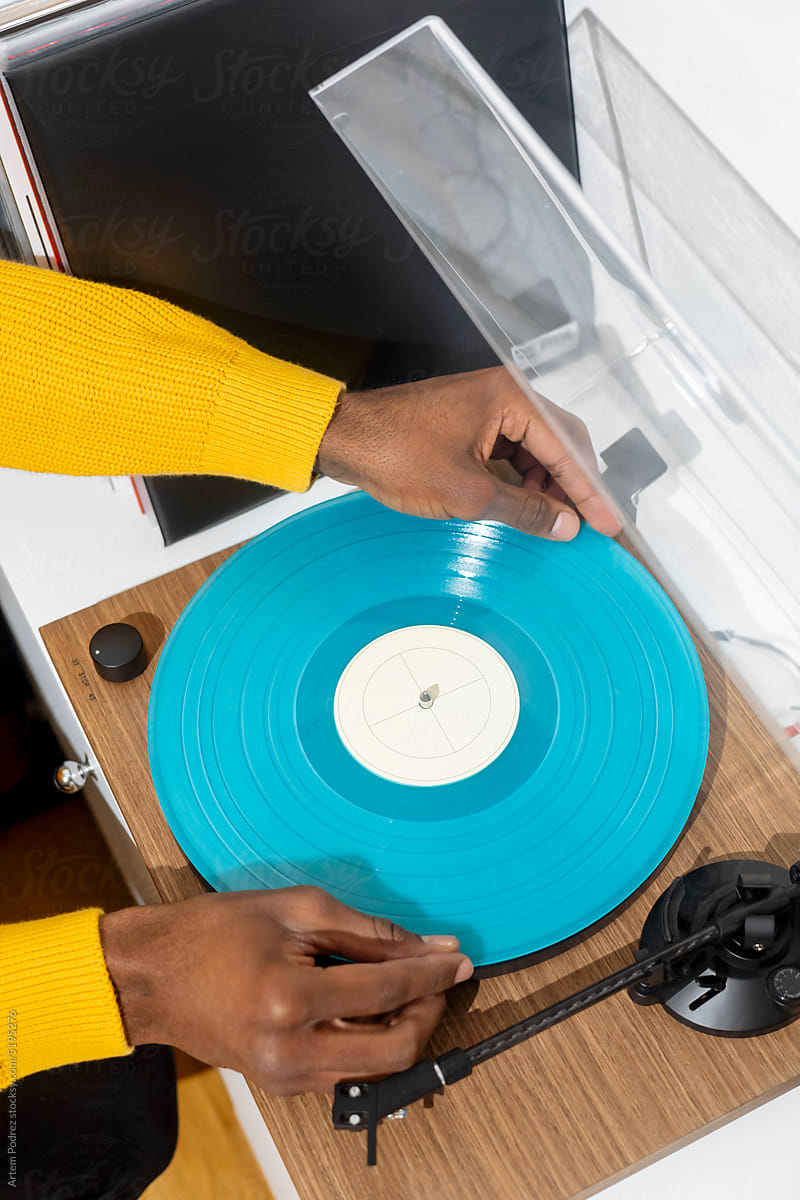 Close-up of black hands installing a vinyl record in a turntable