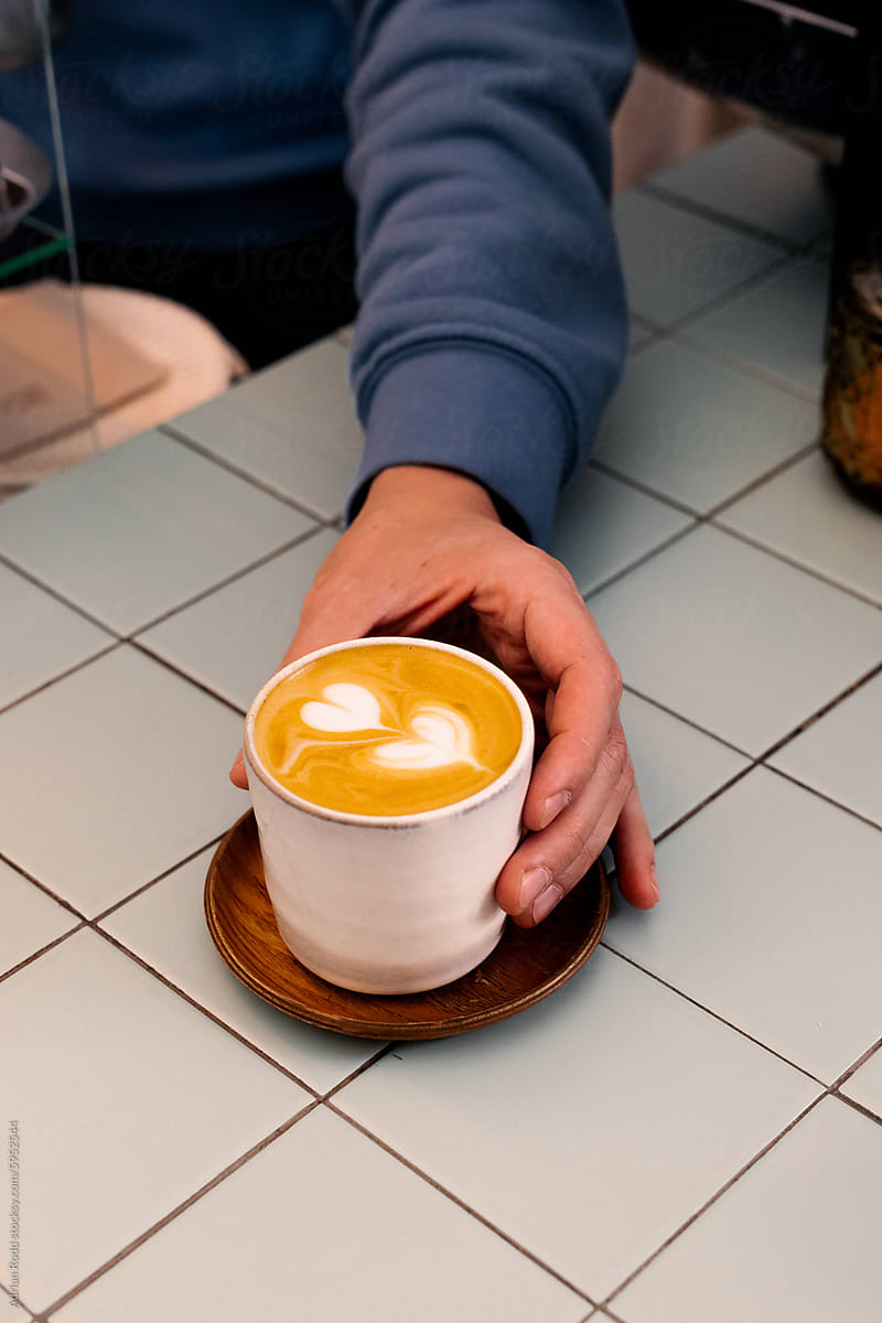 An unidentified barista serves a flat white coffee