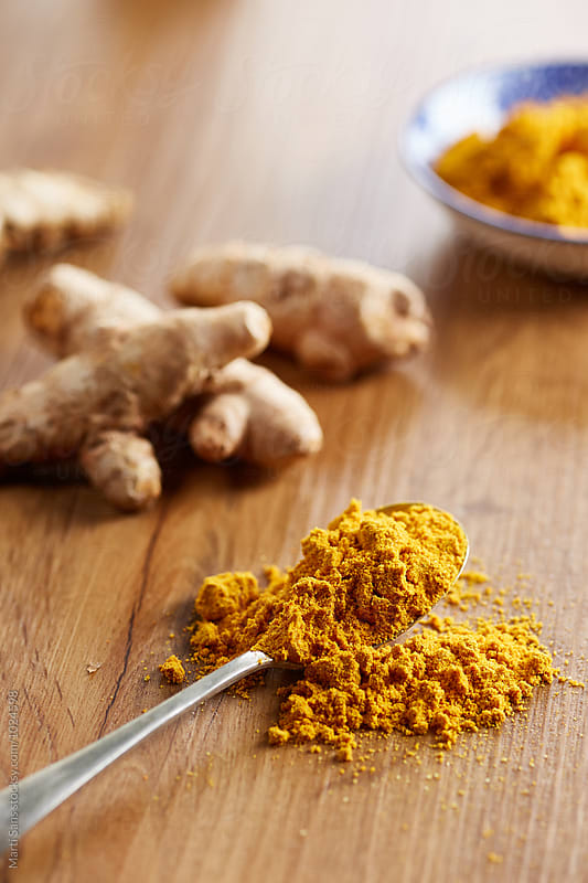 Scatter turmeric powder on spoon and table in close-up
