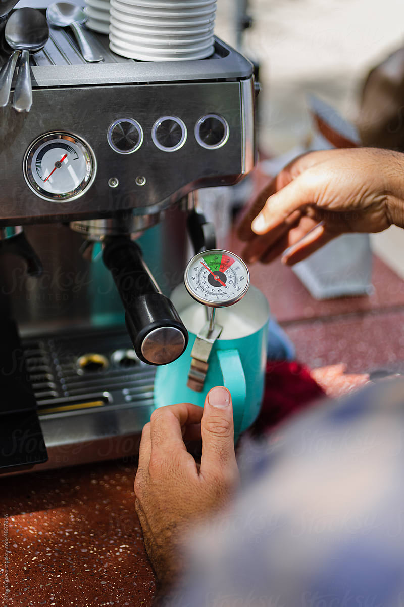 Barista measuring the temperature in front of a espresso machine