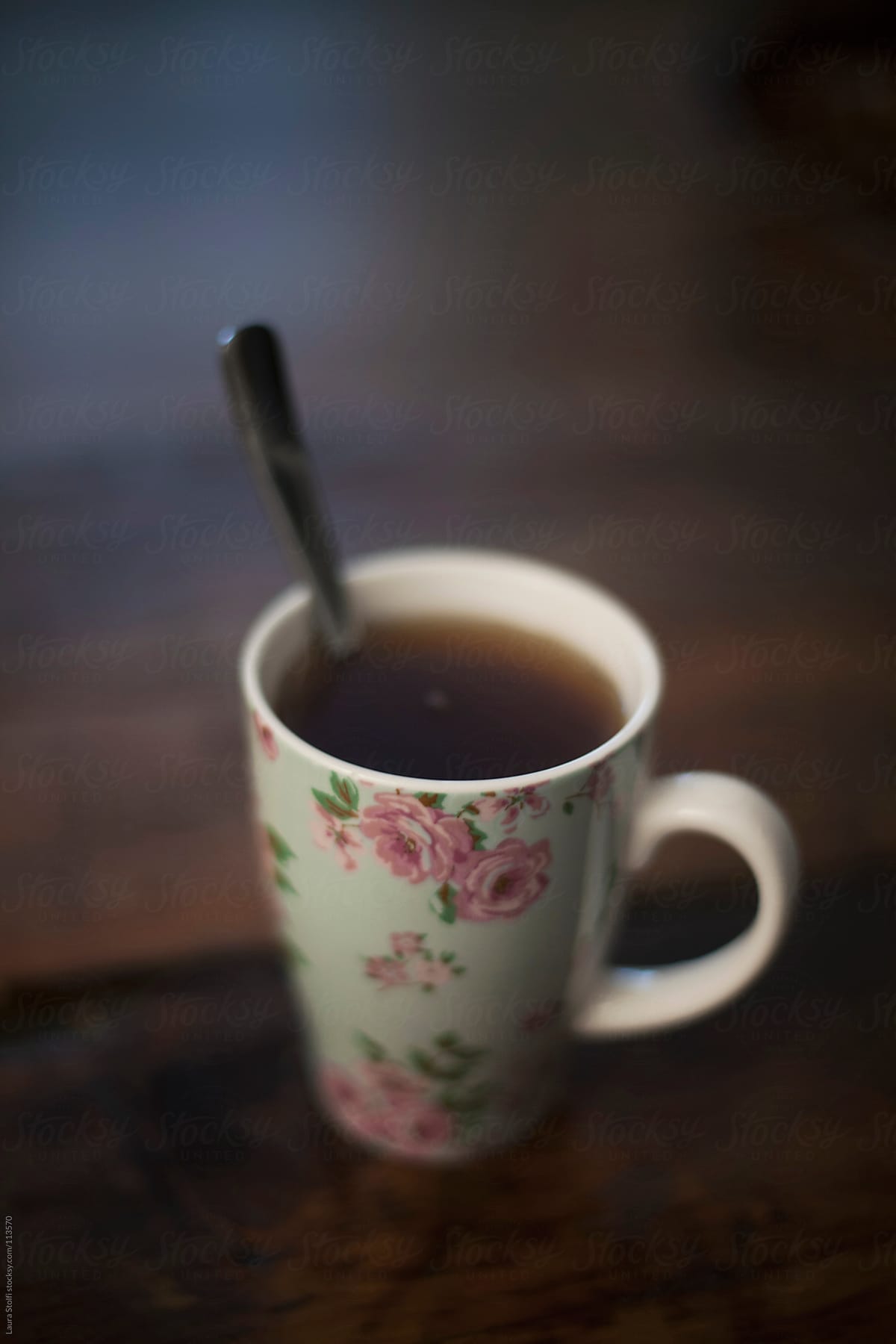 Close-up of flowered china tea mug and spoon on wooden table