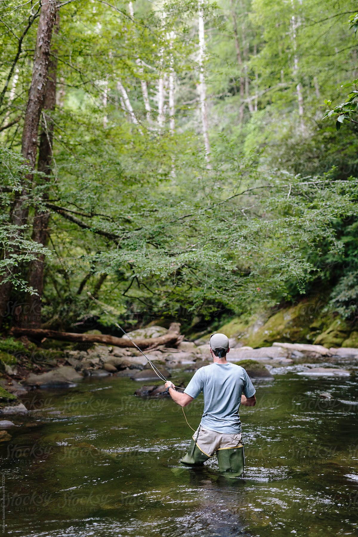 Man Fly-fishing In Clear River Trying To Catch Fish by Stocksy Contributor  Matthew Spaulding - Stocksy
