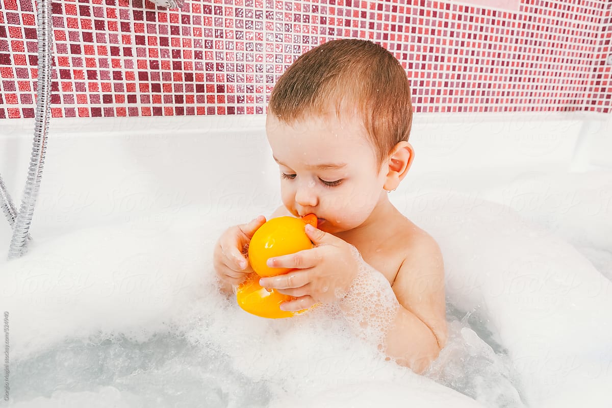 Toddler Kissing his Rubber Duck Toy in the Bathtub