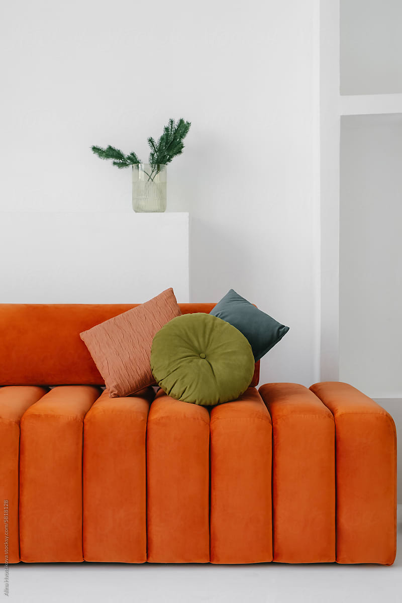 Comfortable orange armless sofa with round back placed at home