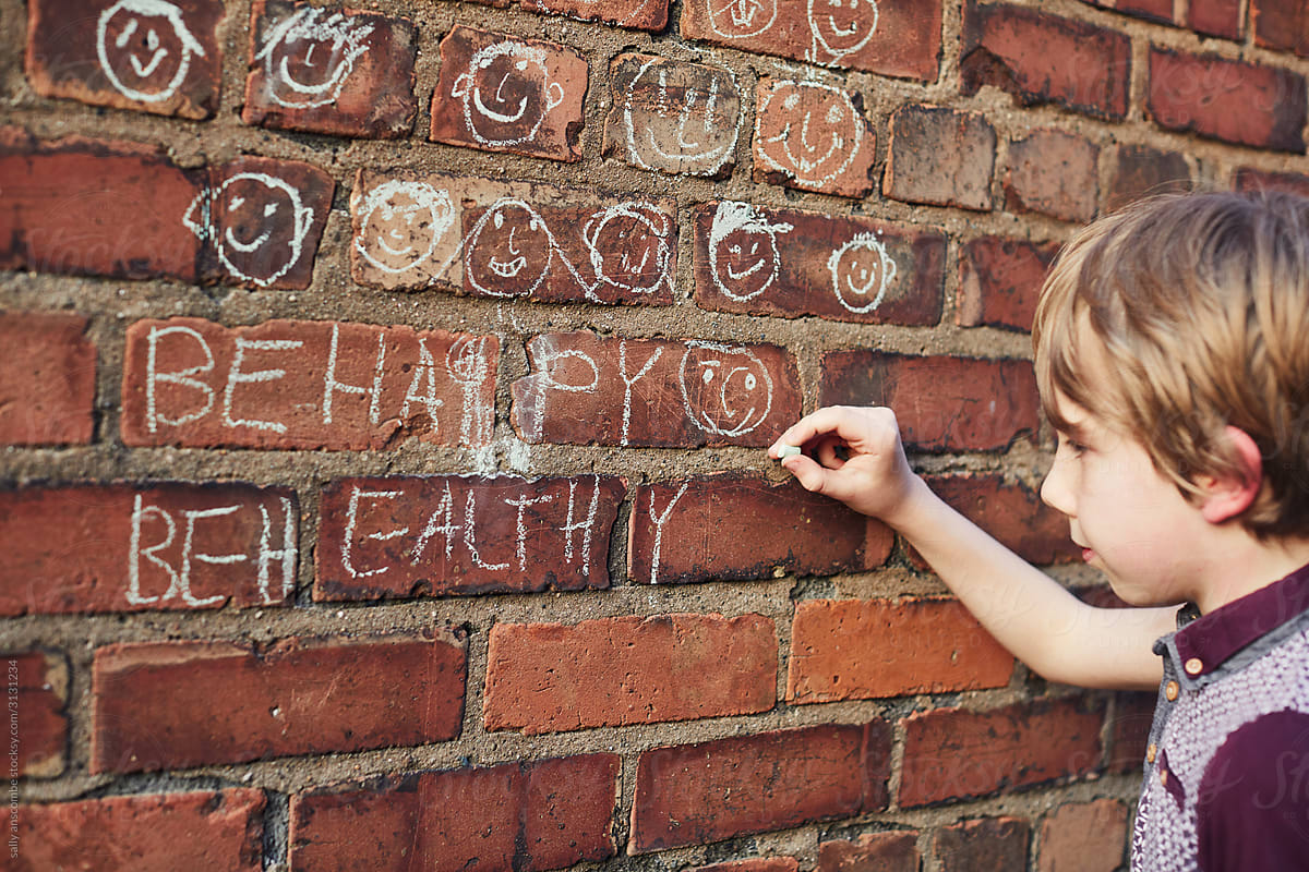 Child drawing with chalk on a brick wall