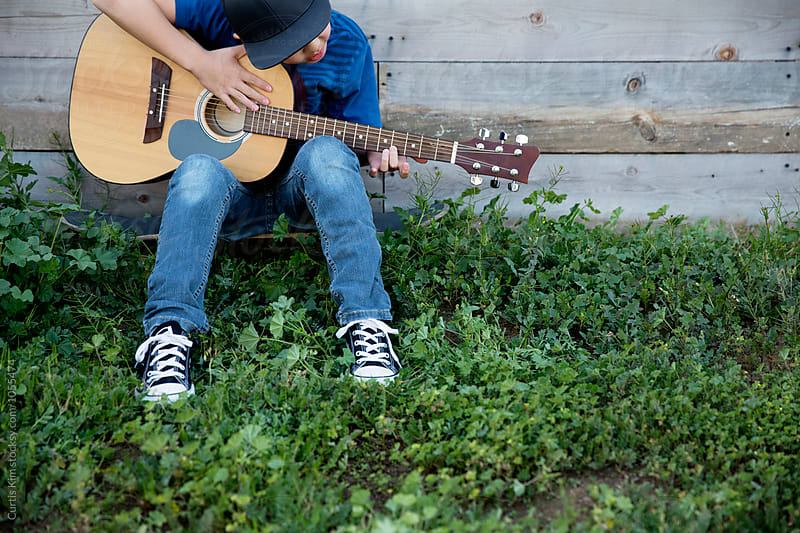 Young boy playing and practicing his guitar