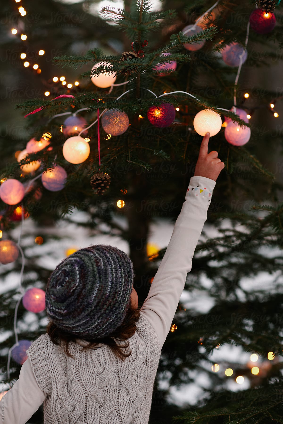Little girl touching a lit ball at the christmas tree