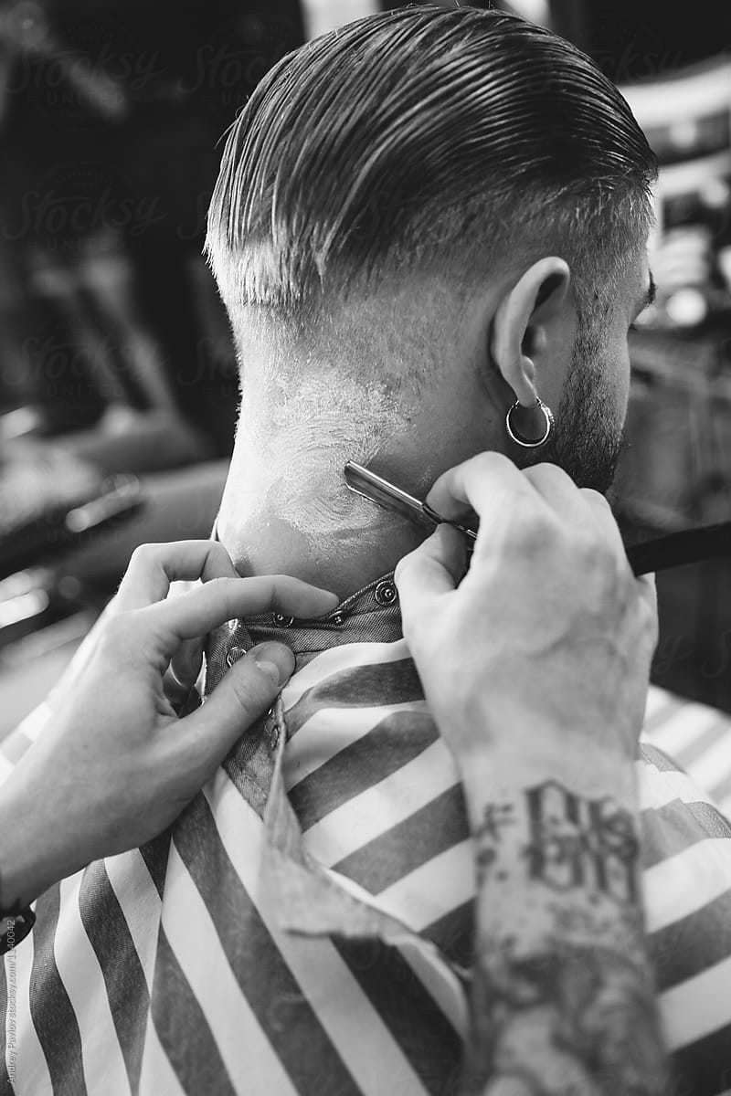 Barber using straight razor to cut man\'s neck