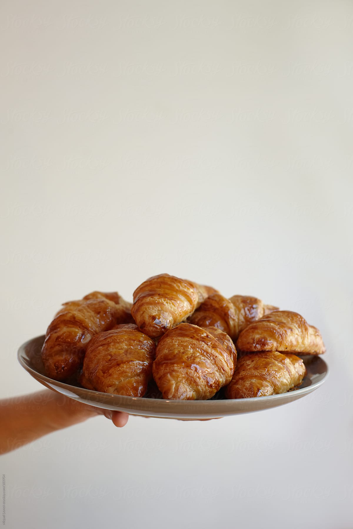 Hand holding a plate of fresh baked croissants