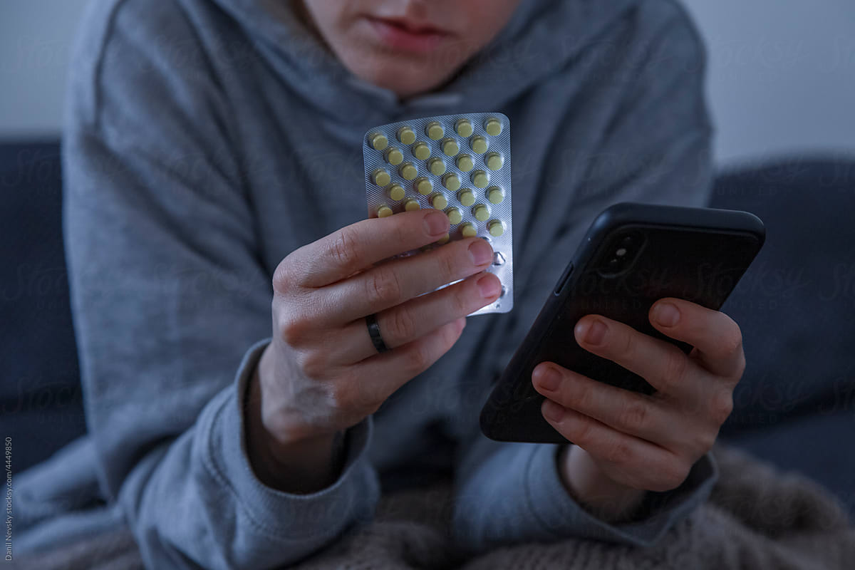 Ill woman reading instruction for pills on smartphone