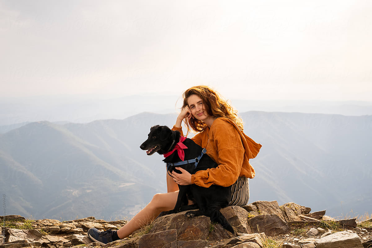 Portrait of young smiley woman with her dog in nature