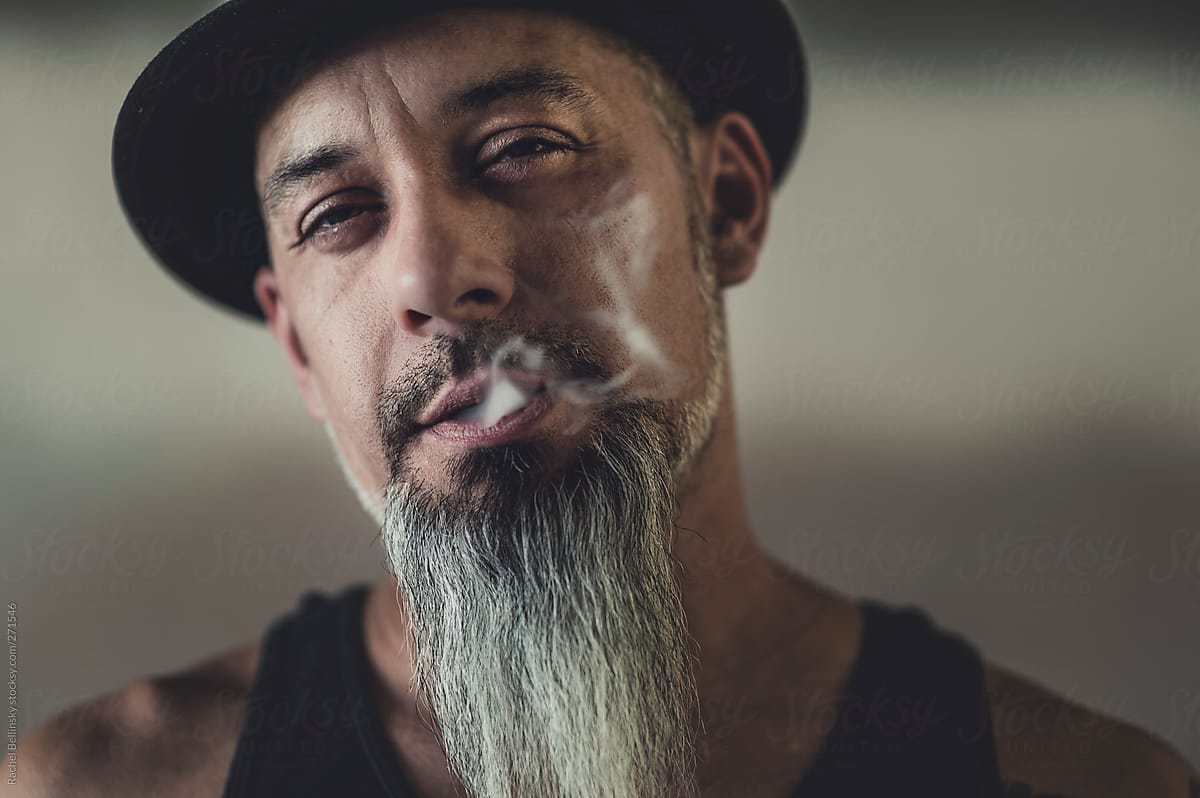 Rugged man with tattoos smokes and gesticulates