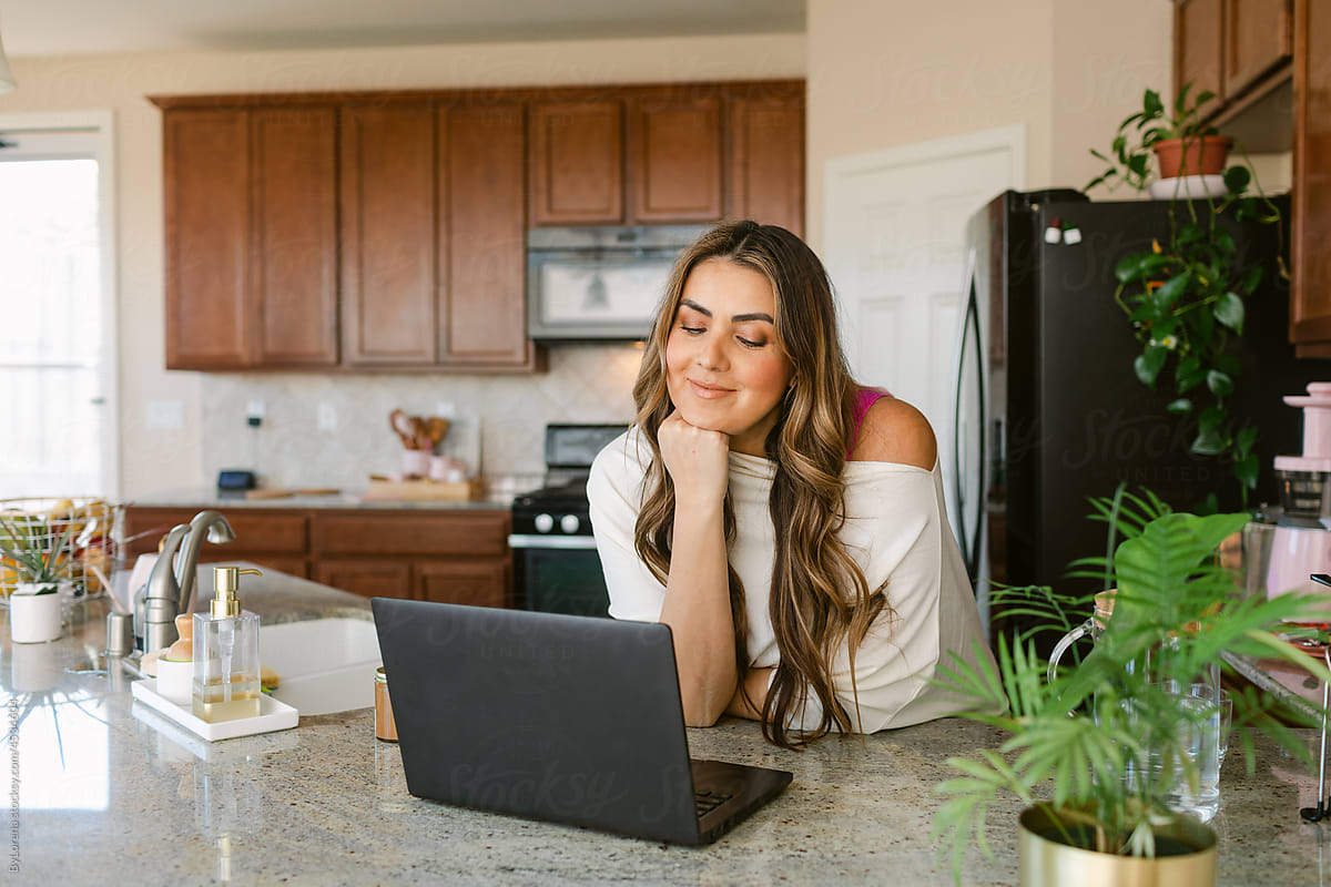 Smiling woman making video chat on laptop in kitchen
