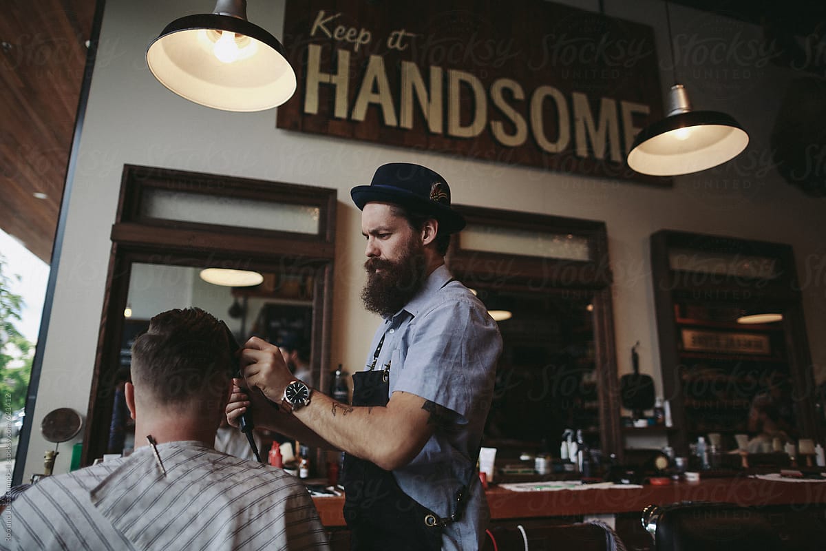 Stylish modern barber giving man a classic haircut using clippers