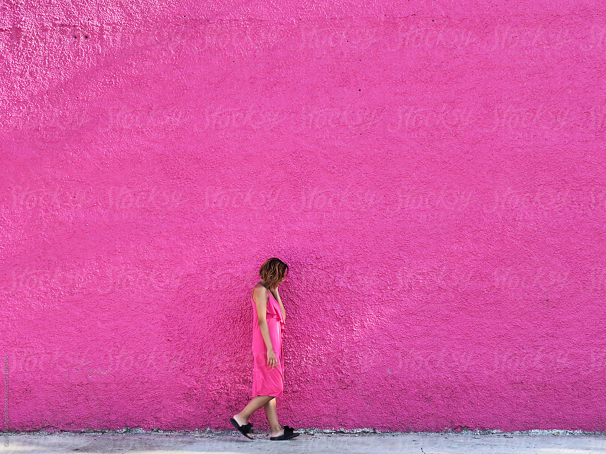 Woman in pink dress against pink wall