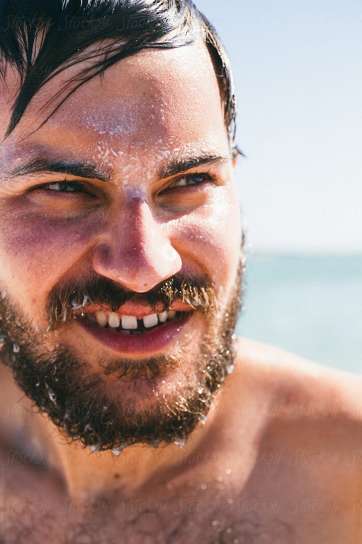 Young man face portrait after taking a bath on the sea with sunscreen on his face