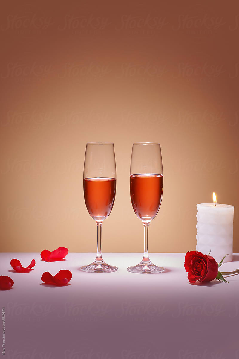 Two glasses of rose wine and red grapes on a colored background.