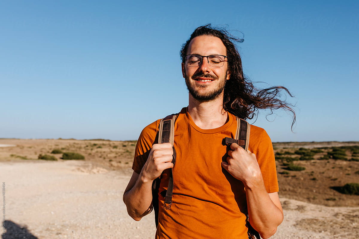 Glad male traveler on windy day in desert